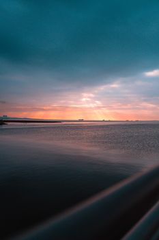Breathtaking sunset view over tranquil ocean waters with light rays through clouds.