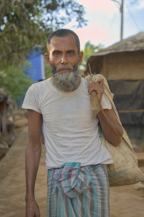 Free Elderly man with a beard carrying a sack outdoors in a rural setting. Stock Photo