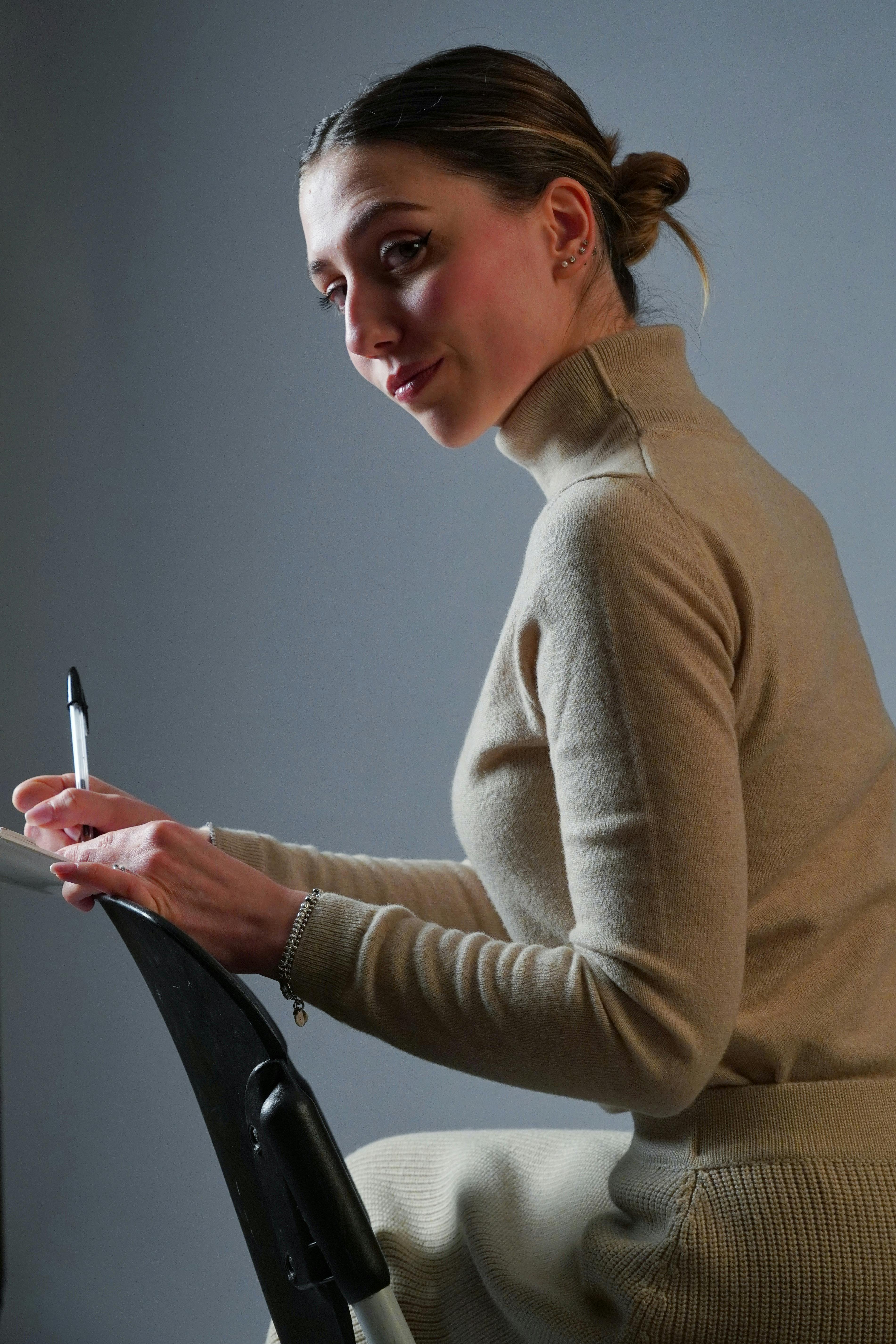 grátis Retrato de uma mulher absorta em pensamentos enquanto escreve, capturando um momento de concentração e criatividade. Foto profissional