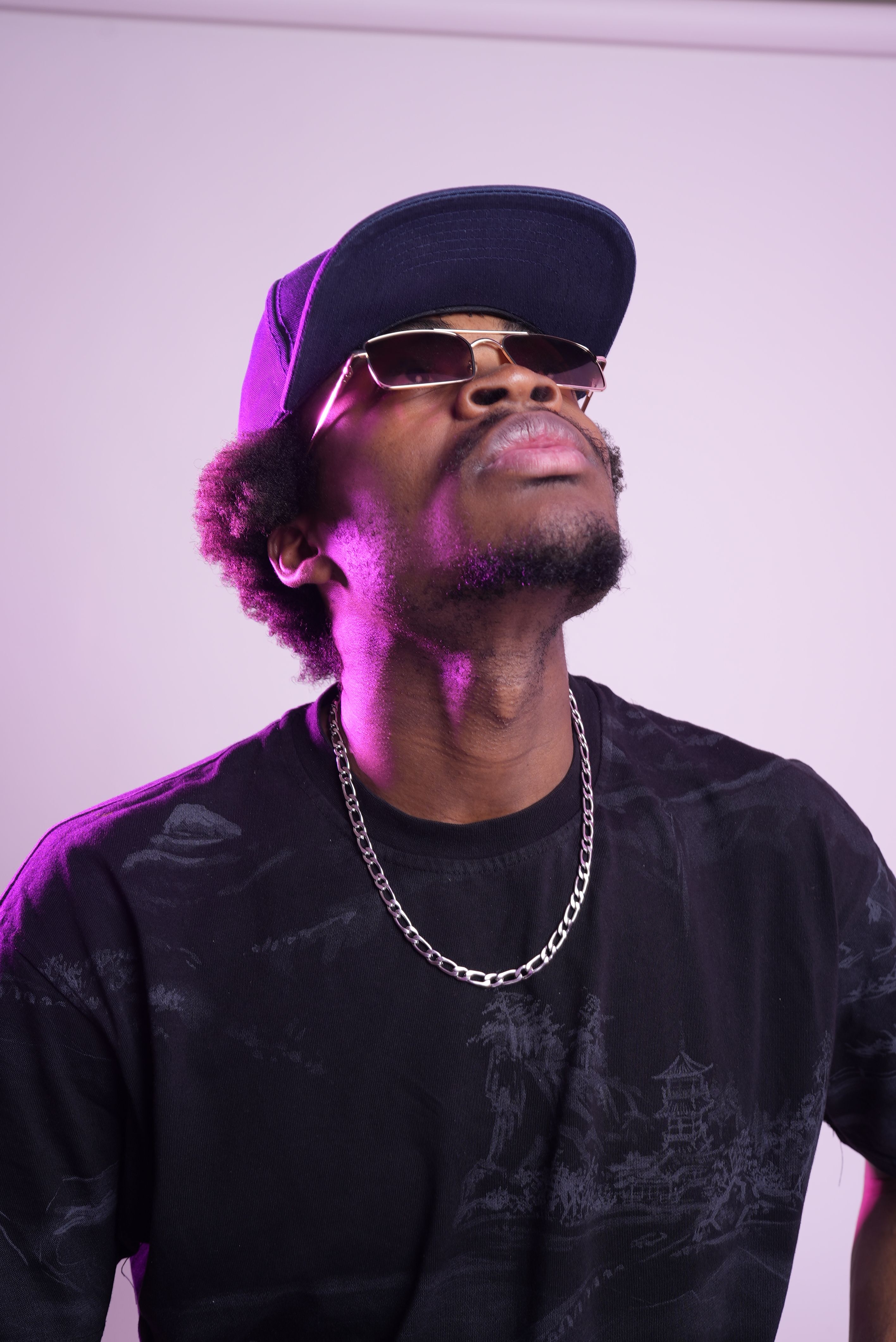 Fashionable man wearing sunglasses and cap posing indoors with a confident look.