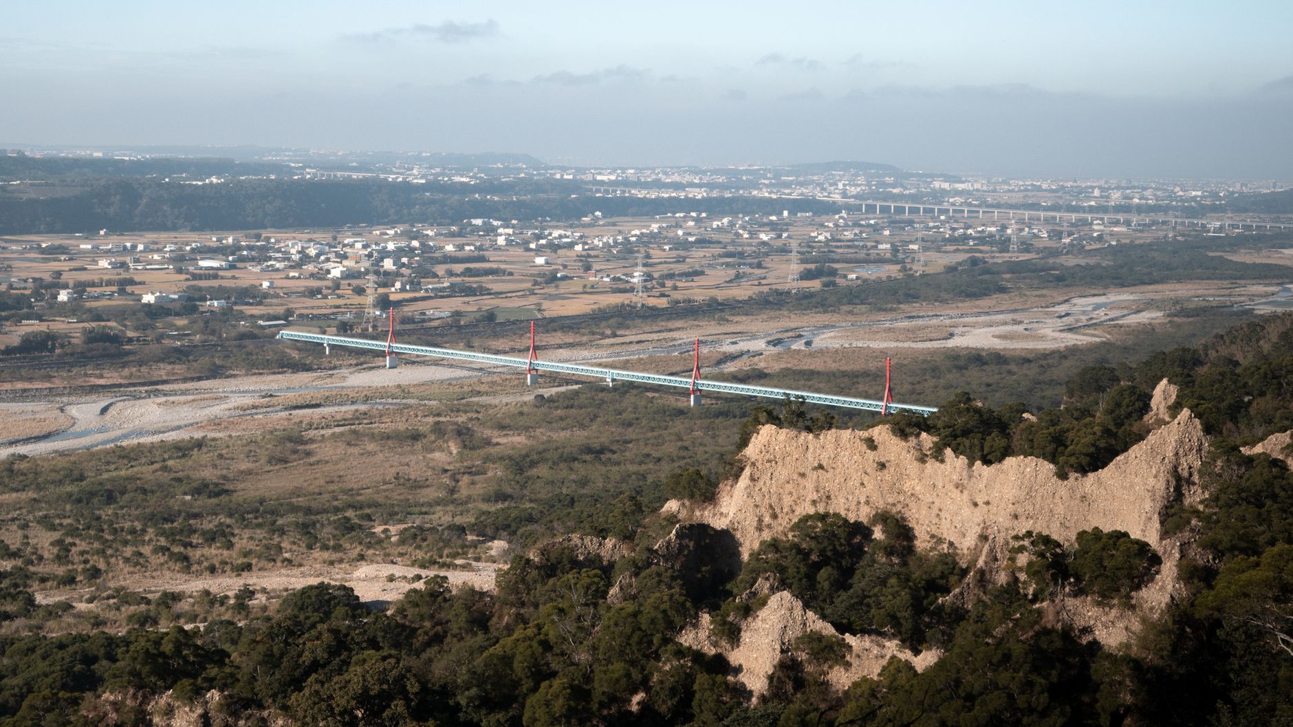 Aerial view of a bridge spanning across a vast landscape in Miaoli County.
