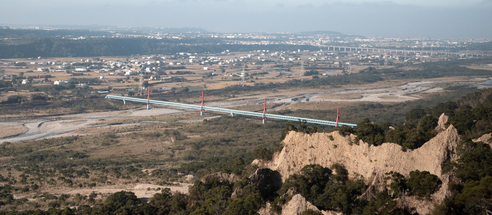 Aerial view of a bridge spanning across a vast landscape in Miaoli County.