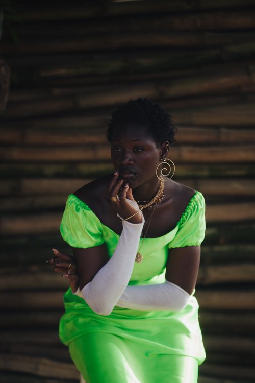 Free Elegant portrait of a woman in a striking green dress, sitting thoughtfully. Stock Photo