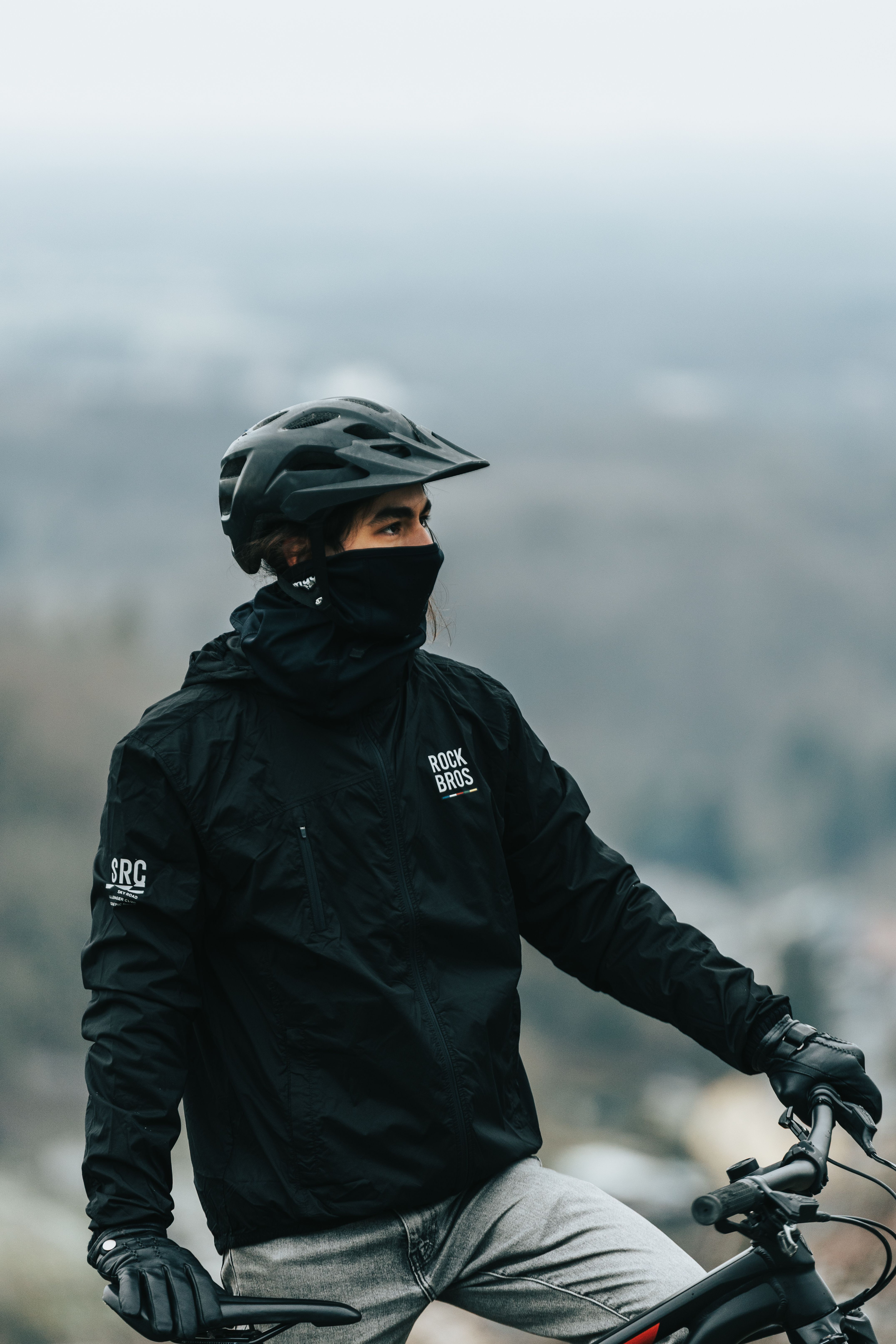 Mountain biker wearing helmet and mask, ready for an adventure in foggy scenery.
