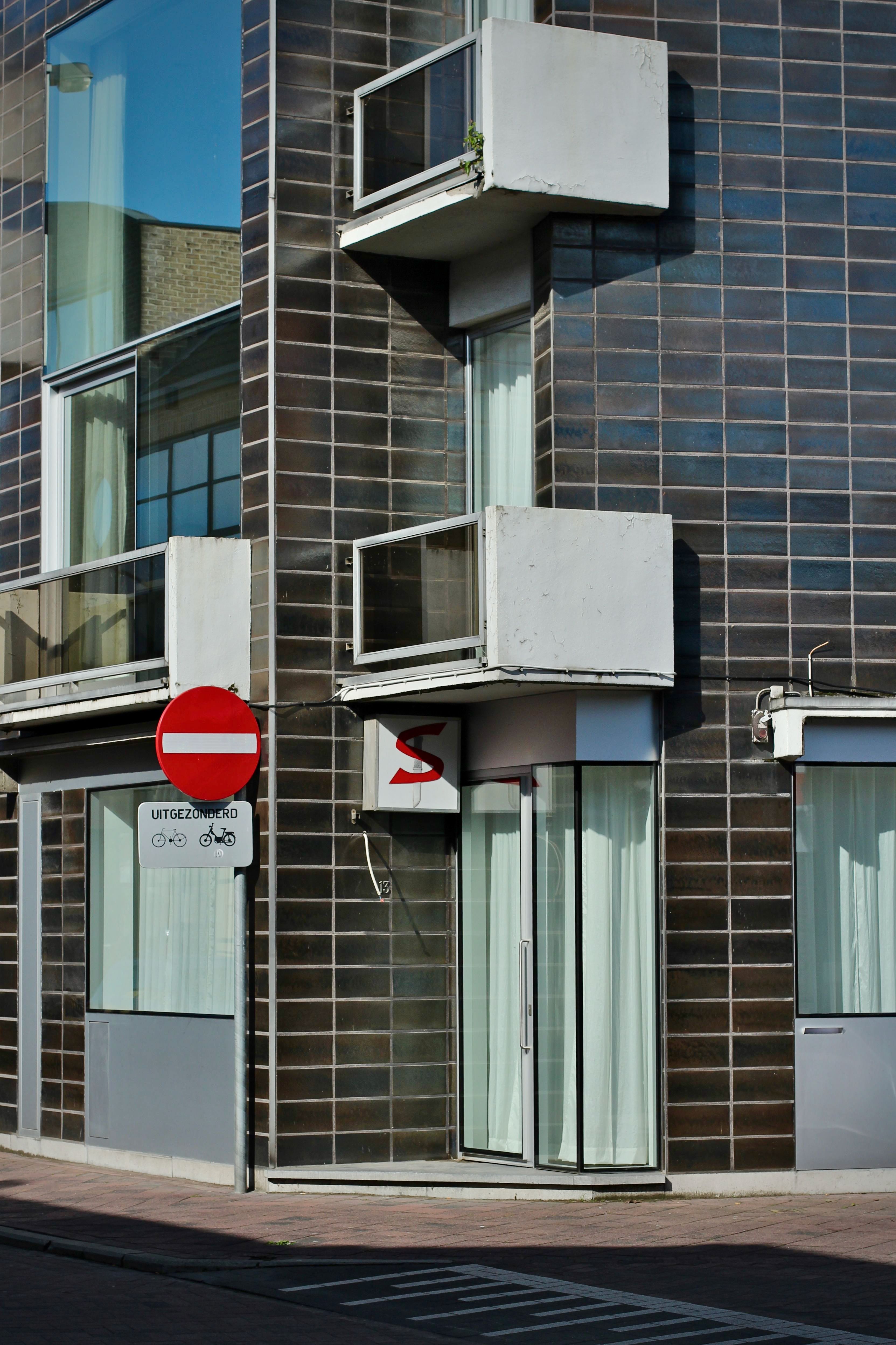 Contemporary urban building facade with a prominent no entry sign and glass windows.