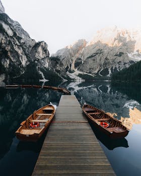 Tranquil scene of boats docked on a serene mountain lake with stunning reflections.