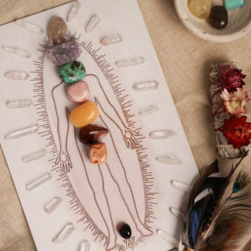 Healing crystals arranged on a chakra body silhouette, illustrating the seven energy centers running along the spine like the Destiny Matrix energy line