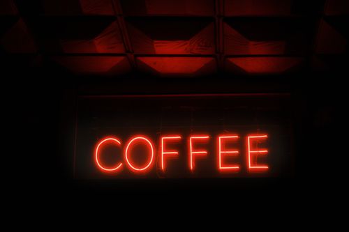 Free A vibrant red neon coffee sign illuminates a dark interior setting. Perfect for coffee shop themes. Stock Photo