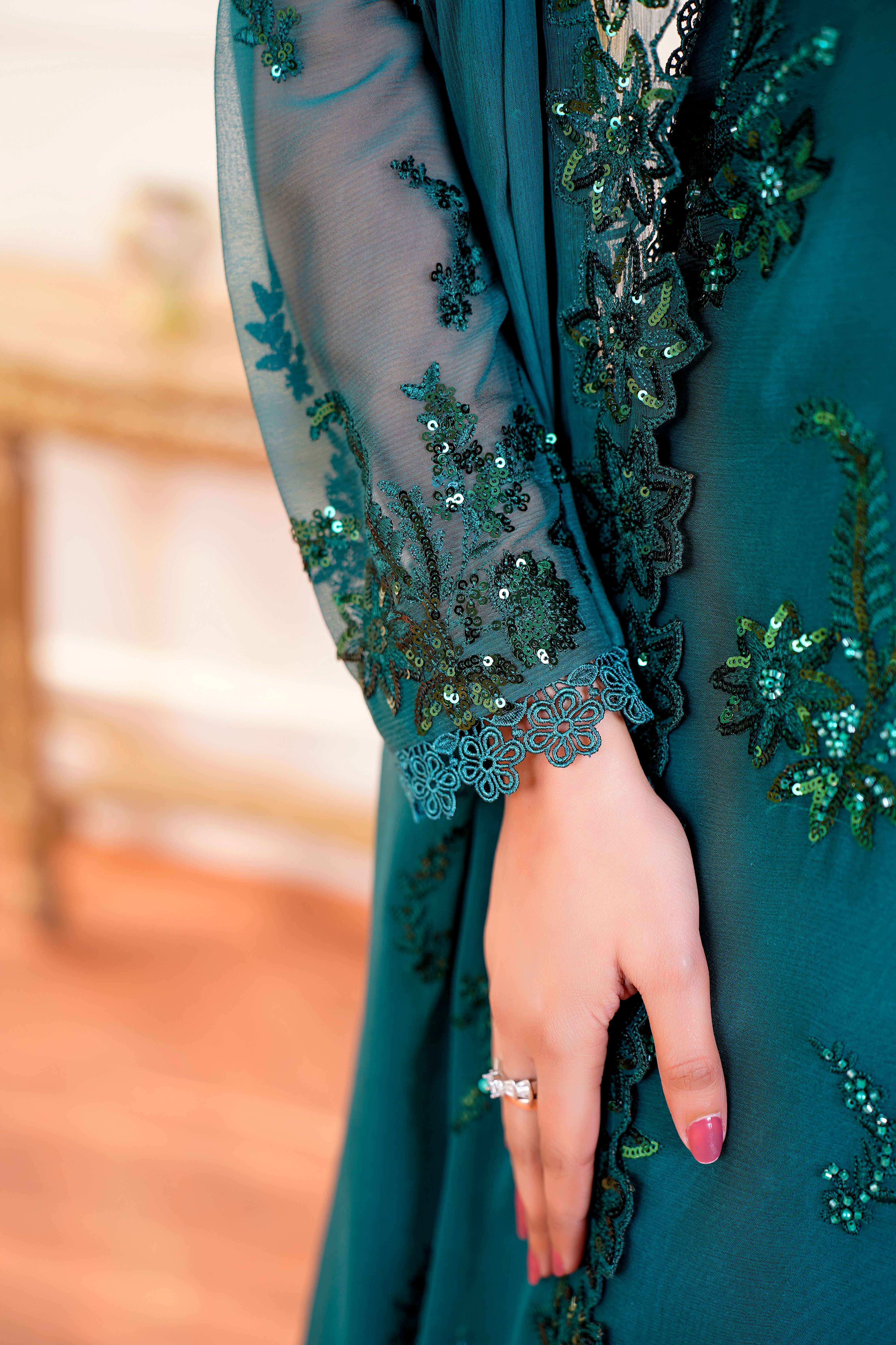 Close-up of a hand wearing an embroidered green chiffon dress, Lahore. - Common Mistakes to Avoid When Choosing Dresses