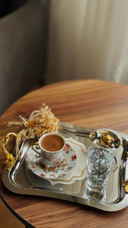 Free A cup of Turkish coffee served with water and delight on a floral plate, capturing elegance and tradition. Stock Photo