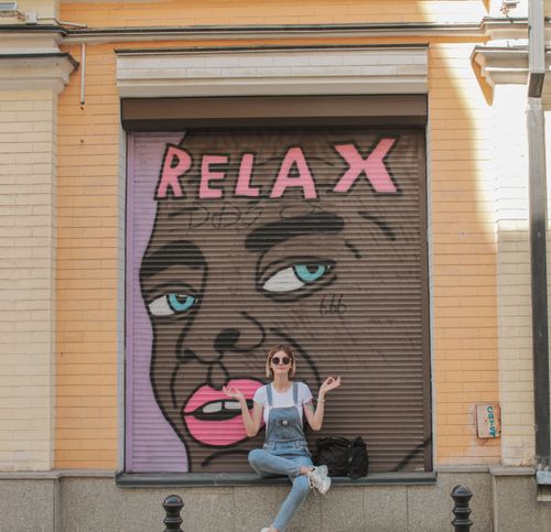 Free Young woman poses in front of colorful graffiti in Kyiv, Ukraine, enjoying a sunny day. Stock Photo