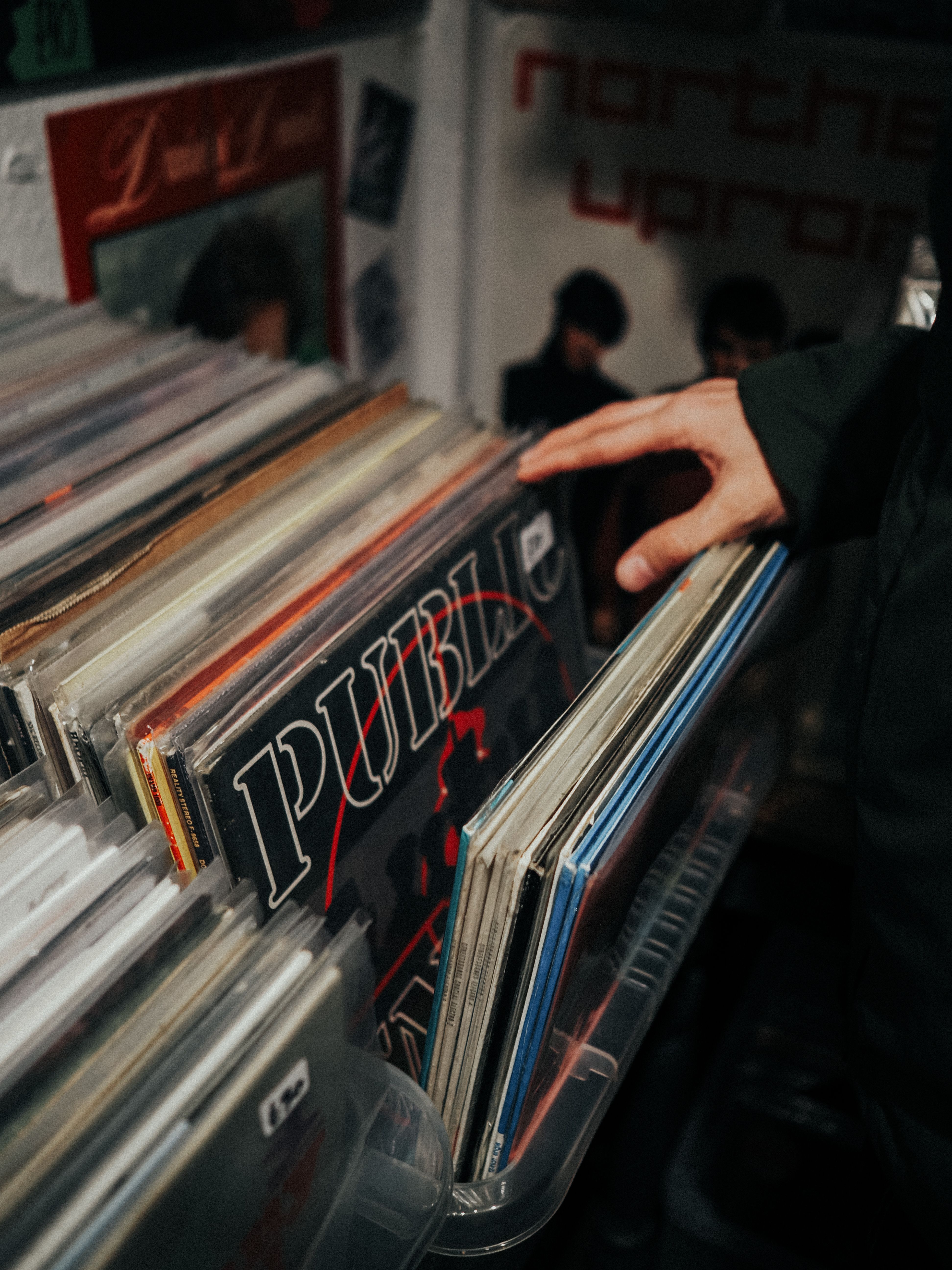 A person browsing a collection of vinyl records in a cozy Abergele shop.