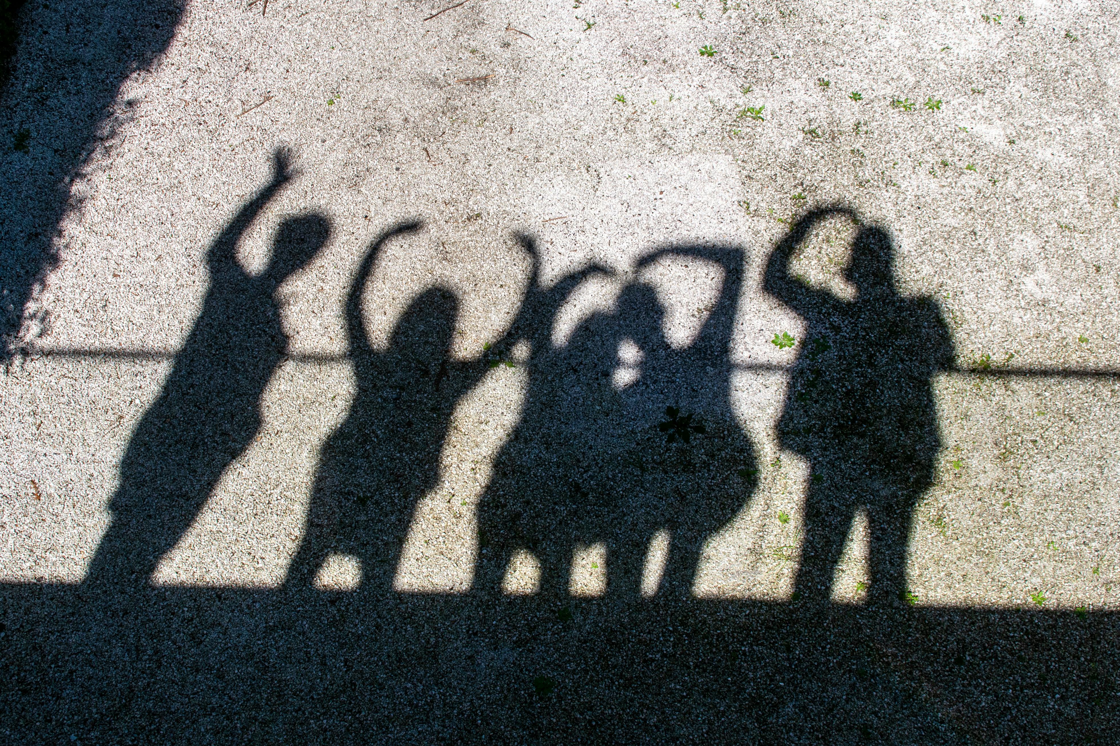 Zadarmo Siluety ľudí vrhajú tiene na chodník a so zdvihnutými rukami vytvárajú hravú scénu. Fotka z fotobanky