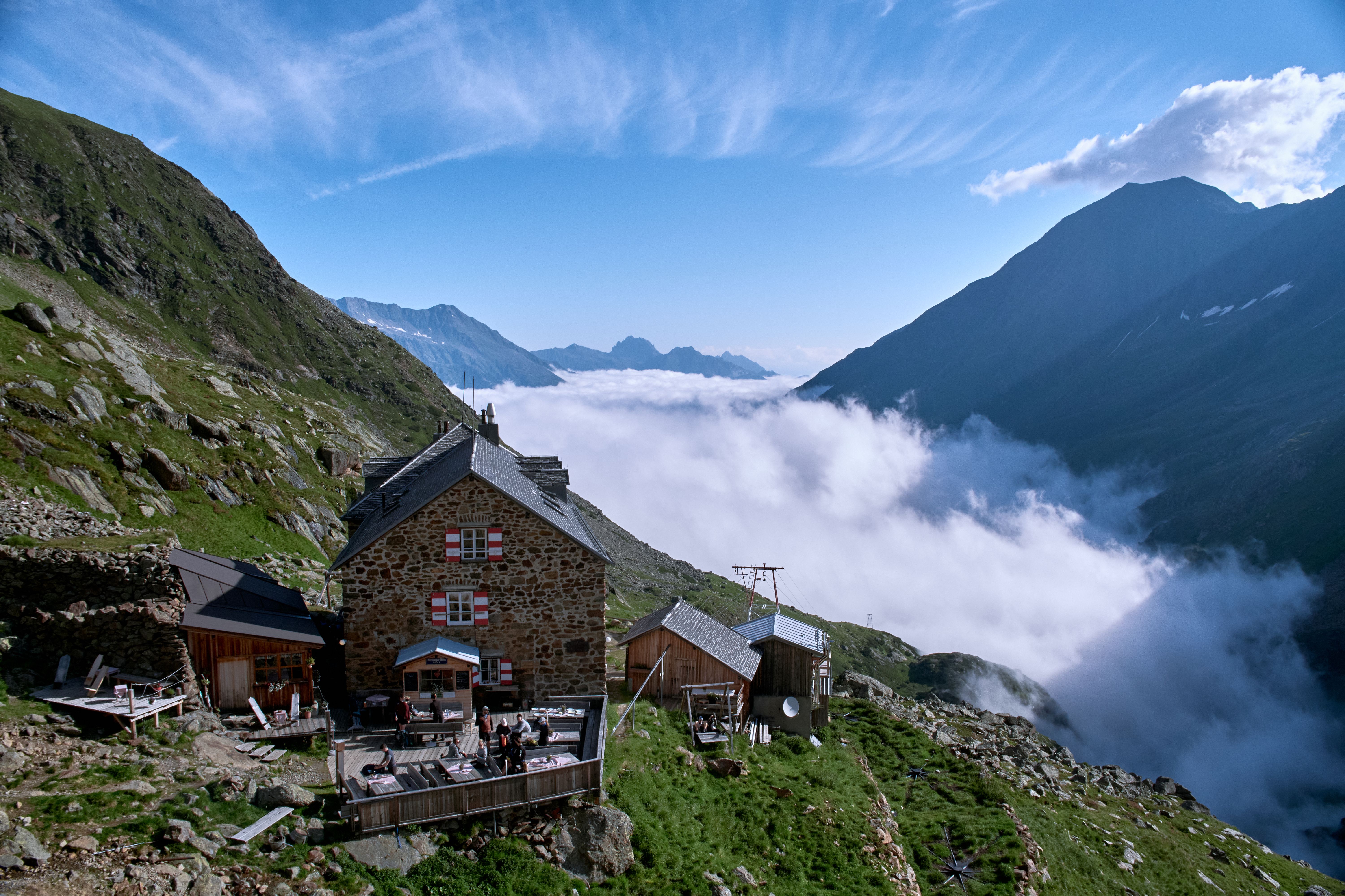 Chalet alpin paisible offrant une vue panoramique sur les Alpes autrichiennes et les nuages ​​en contrebas, refuge idéal en pleine nature.