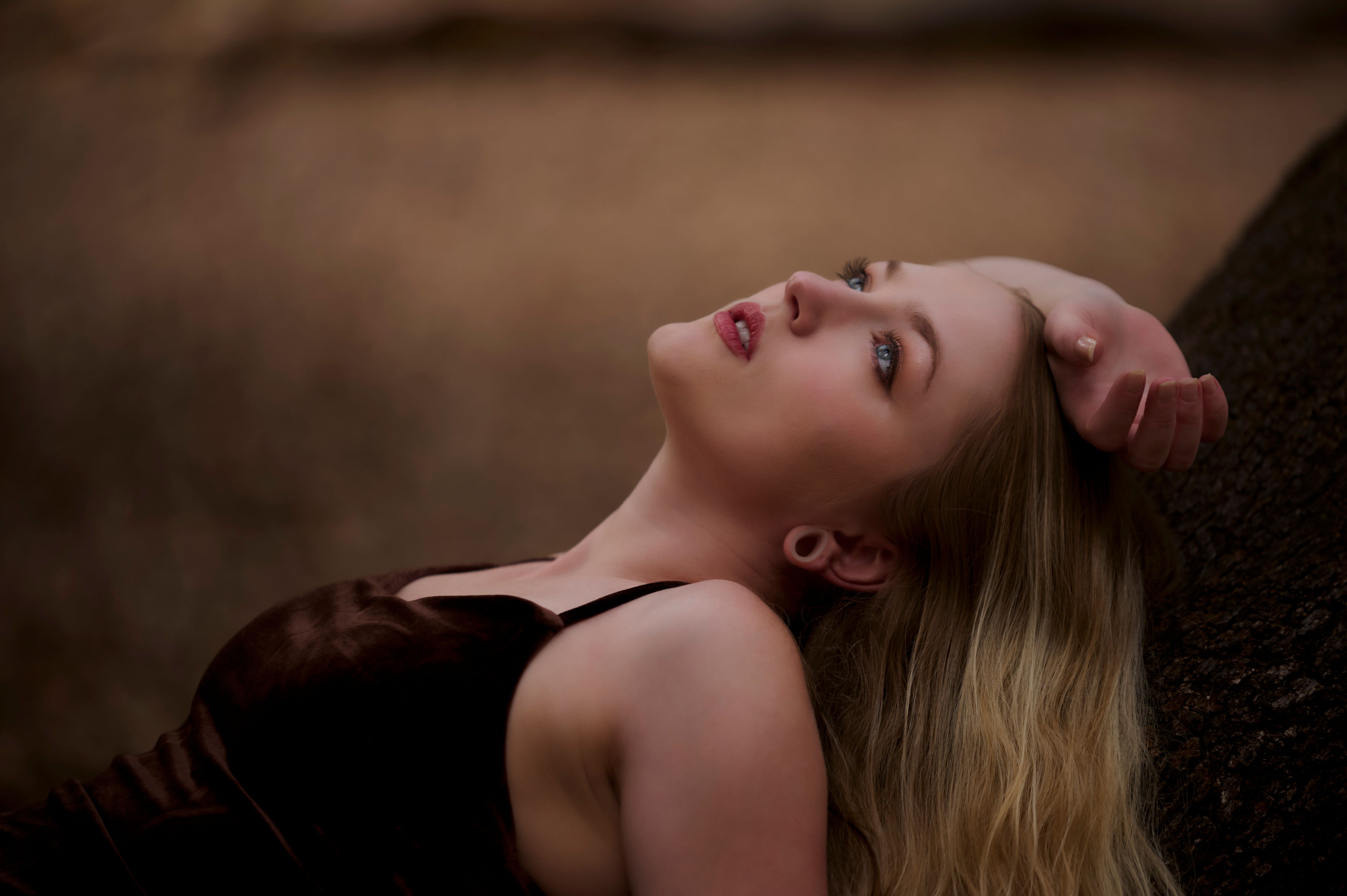 A serene outdoor portrait of a woman reclining against a tree, evoking calmness.