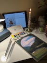 Cozy Art Workspace with Watercolors and Candlelight