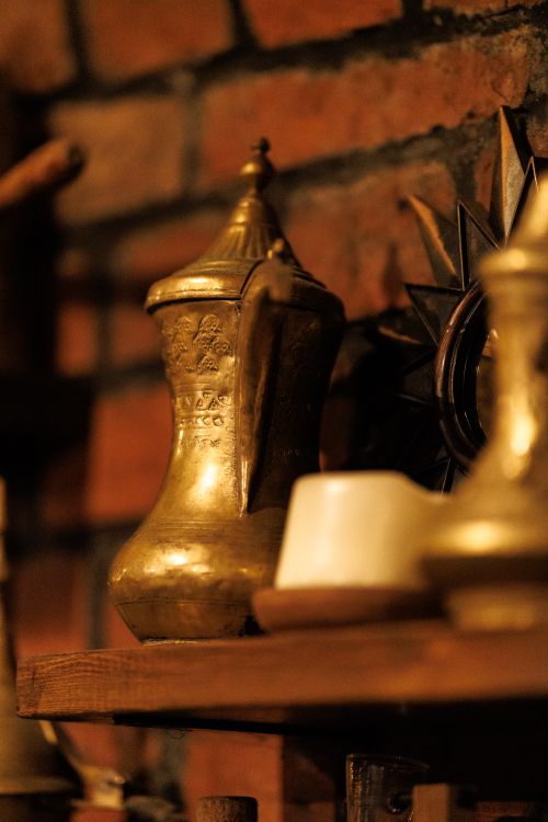 Free Antique brass coffee pot with warm light on a rustic shelf in Kaliningrad interior. Stock Photo