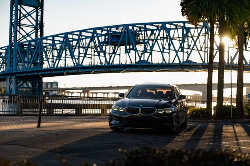 Free Stylish car parked under a bridge during a beautiful urban sunset, capturing city life. Stock Photo