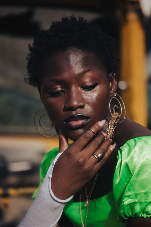 Free Close-up portrait of a stylish woman with afro hairstyle wearing green top and gold earrings. Stock Photo