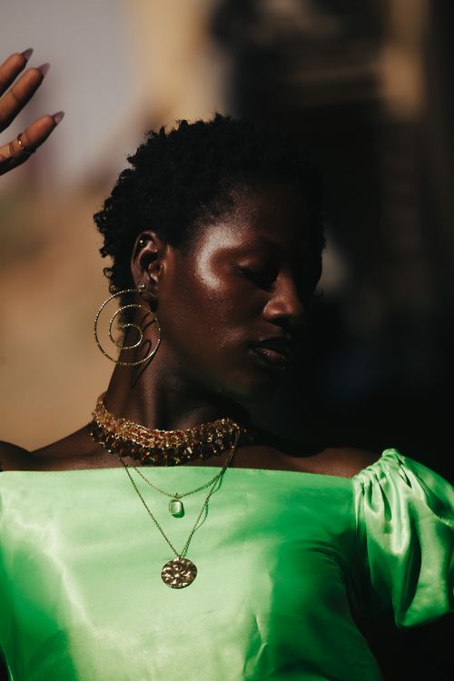 Free Elegant portrait of a woman in vibrant green satin, showcasing striking jewelry. Stock Photo