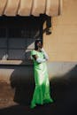 Elegant Woman in Green Dress by Sunlit Wall