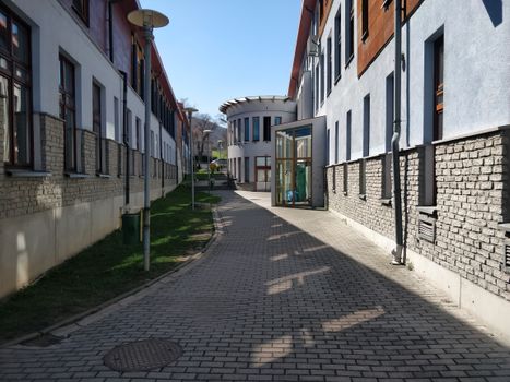 A sunny outdoor passage between modern educational buildings with brick facades.