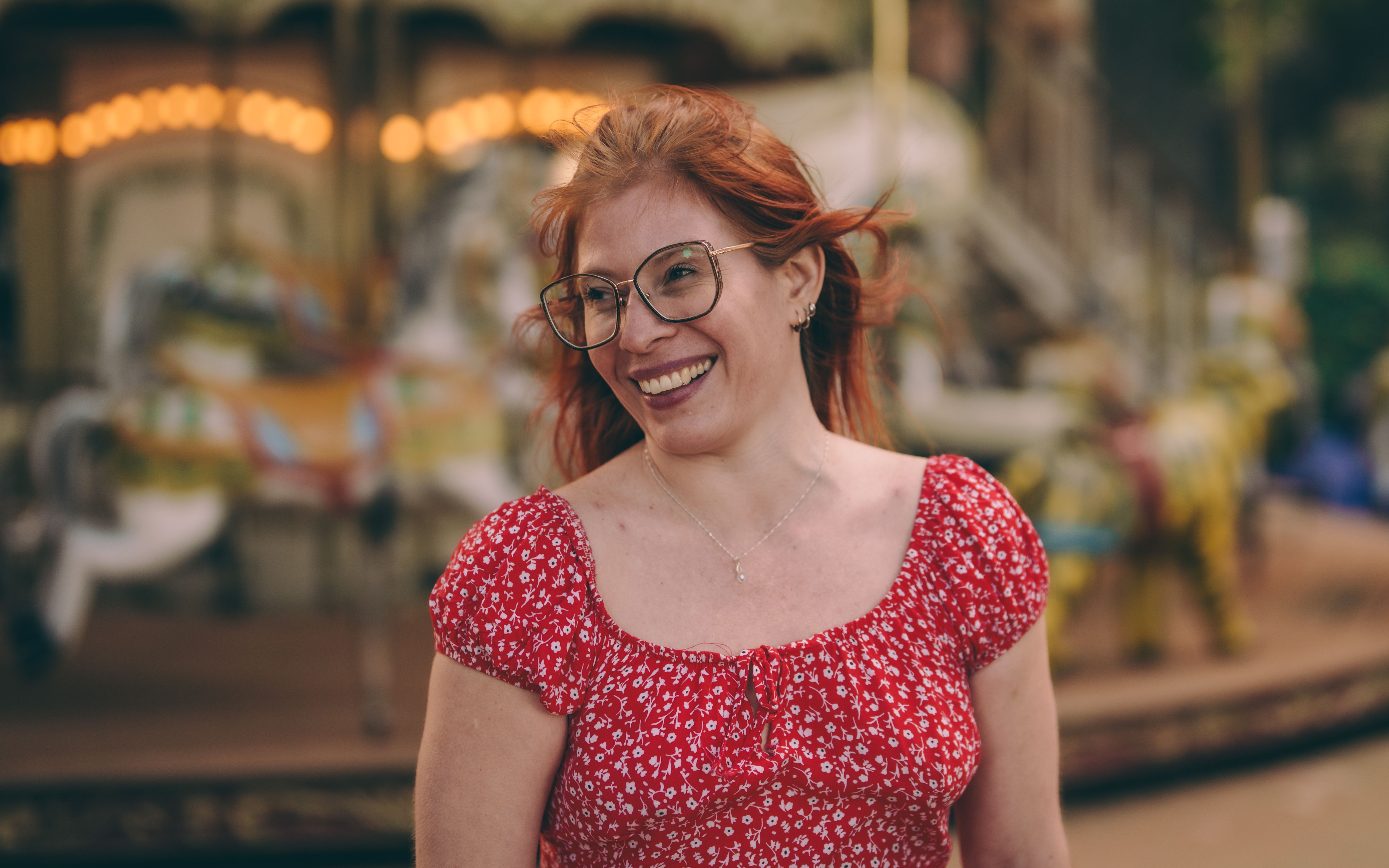 Smiling Woman in Red Dress Near Carousel · Free Stock Photo