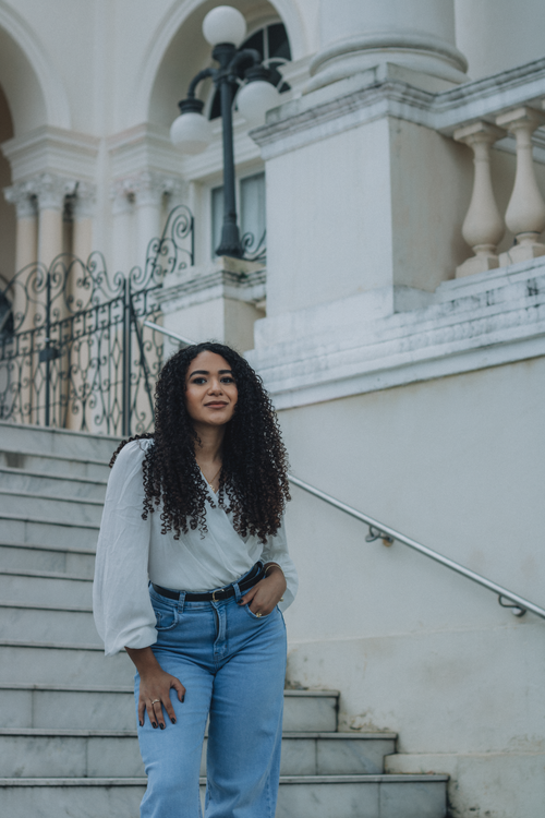 Free Young woman with curly hair posing on ornate outdoor staircase. Stylish and sophisticated. Stock Photo