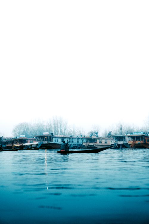Free Calm riverside view featuring boats and houses, perfect for a tranquil and peaceful mood. Stock Photo