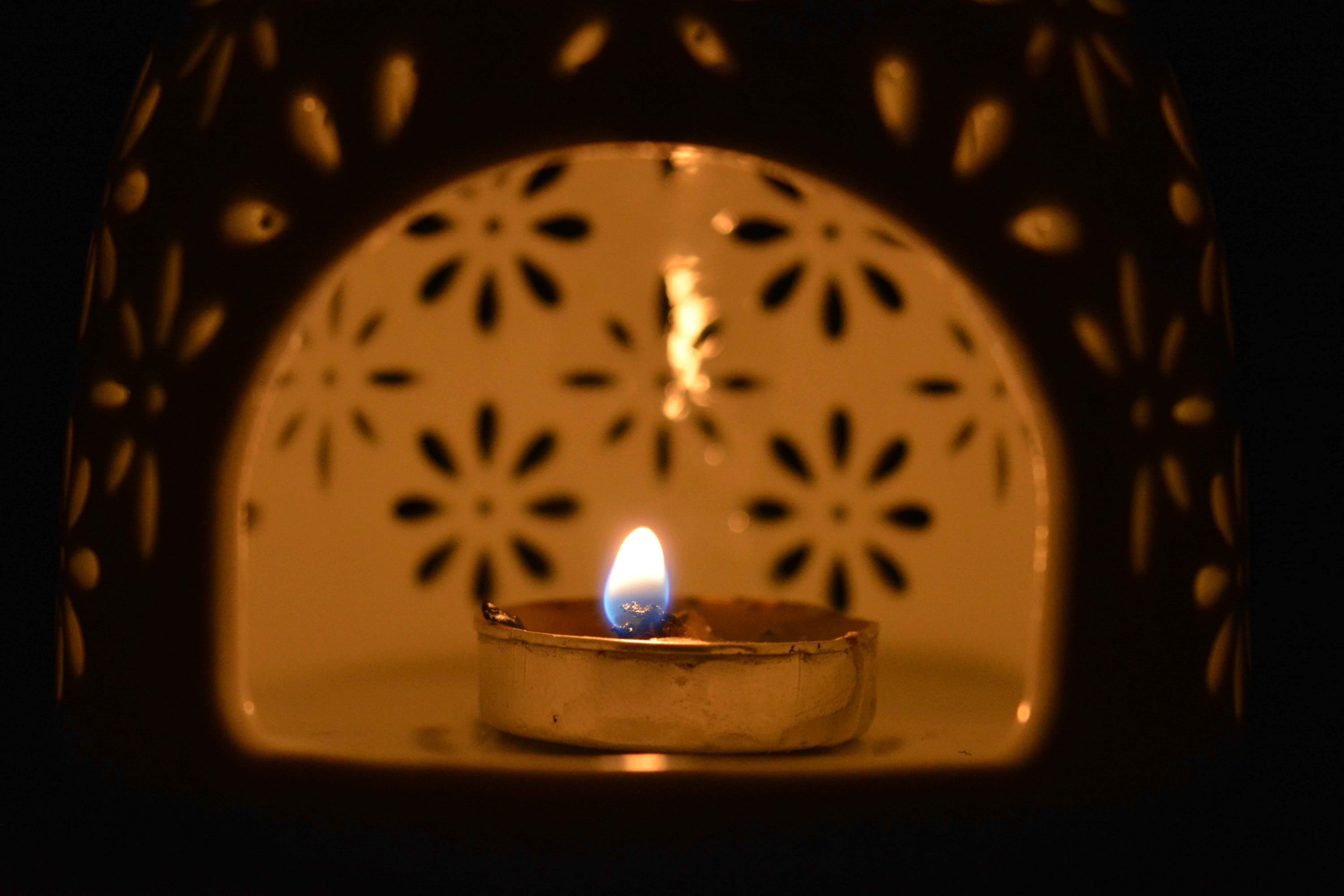 A calming candle flame glows within a floral-patterned ceramic holder, creating a warm ambiance.