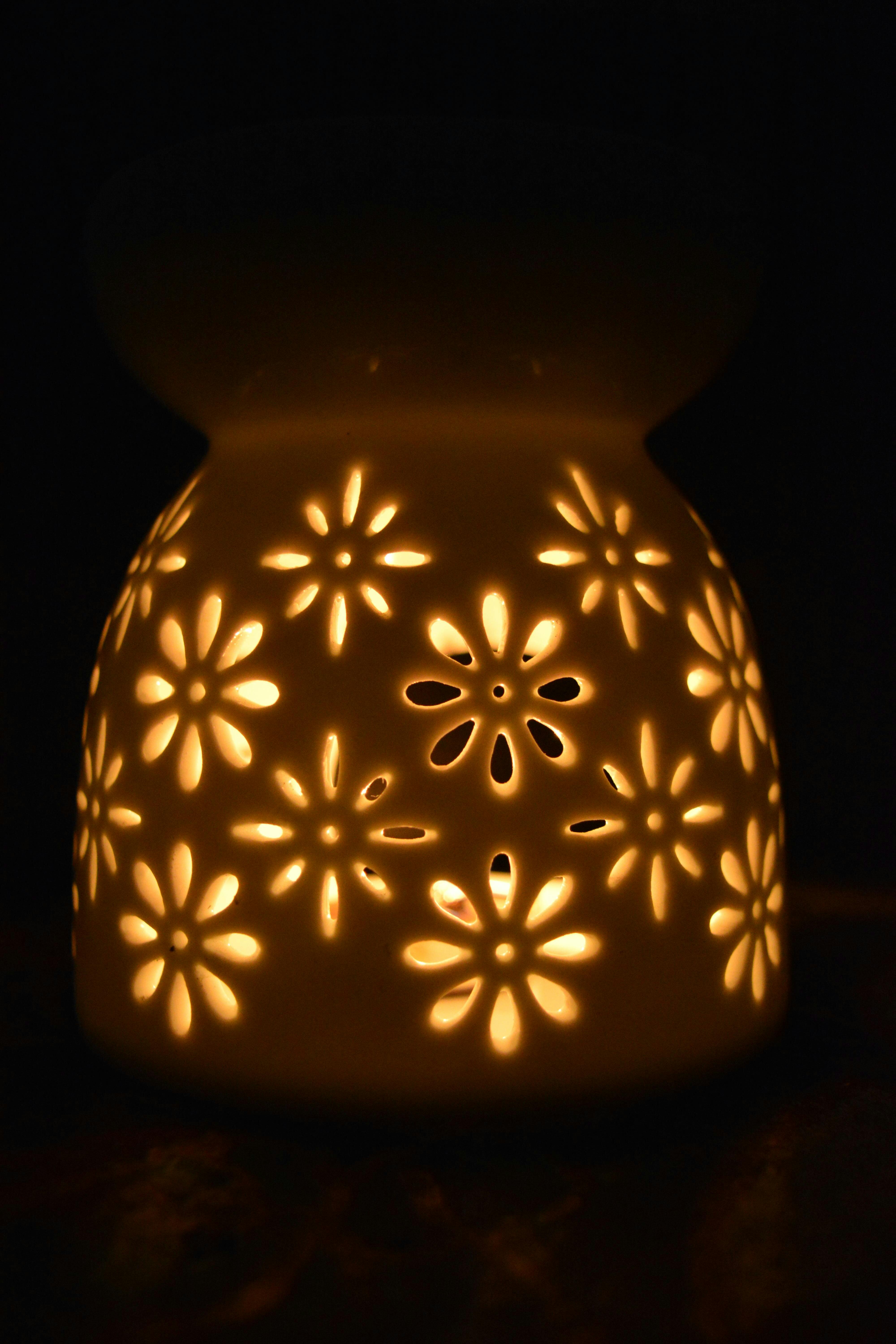 A glowing ceramic candle holder with floral cutouts creates a warm, meditative ambiance.