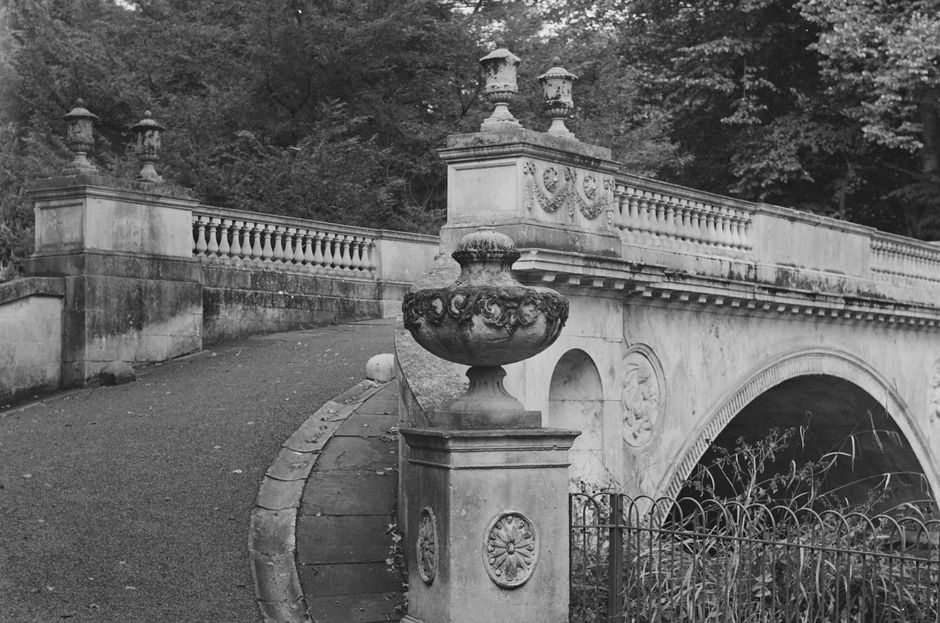 Black and white photo of a vintage stone bridge in England's lush landscape.