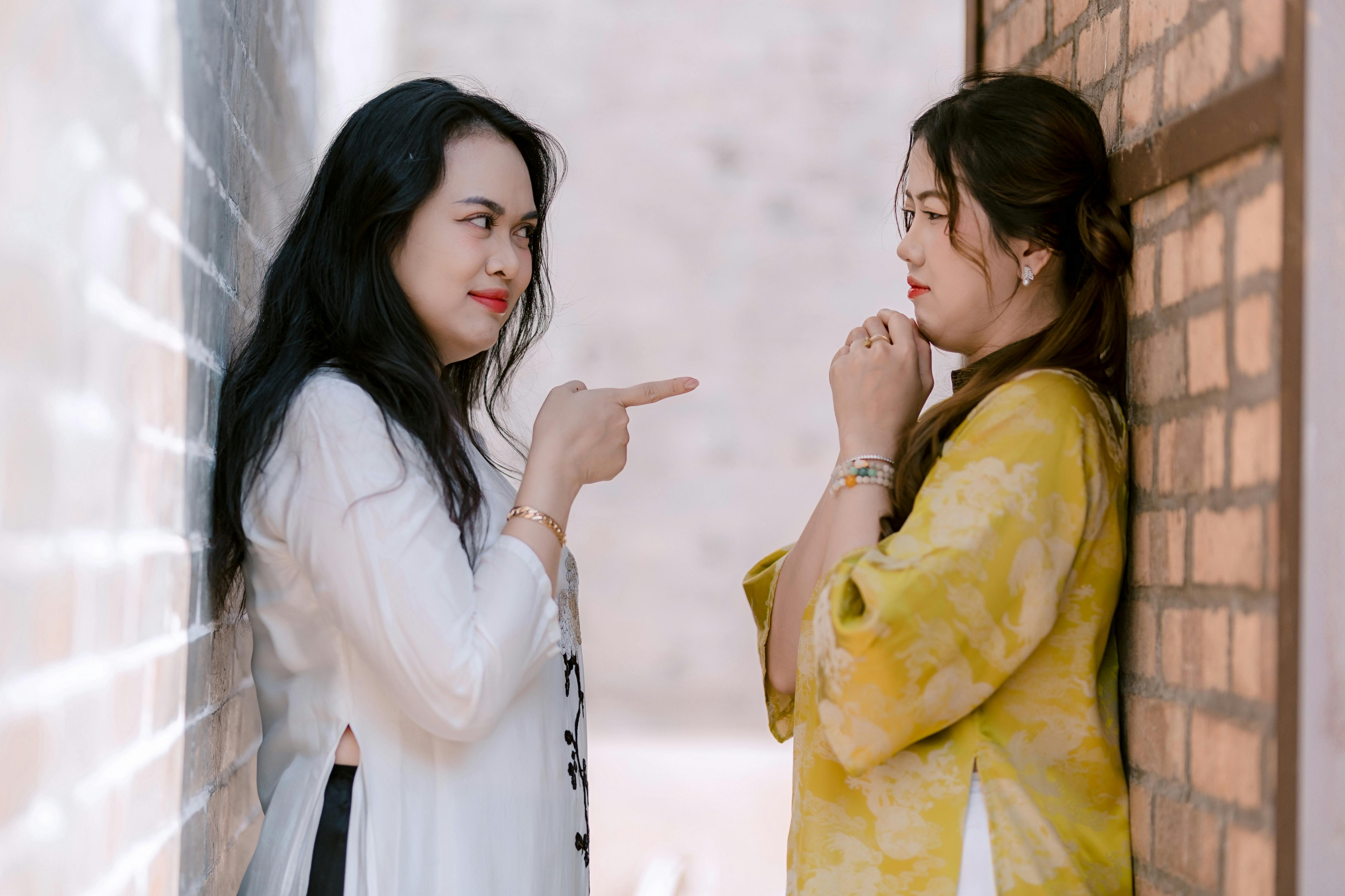 Two women interact in a narrow alleyway with a playful stance, bringing attention to their expressions.