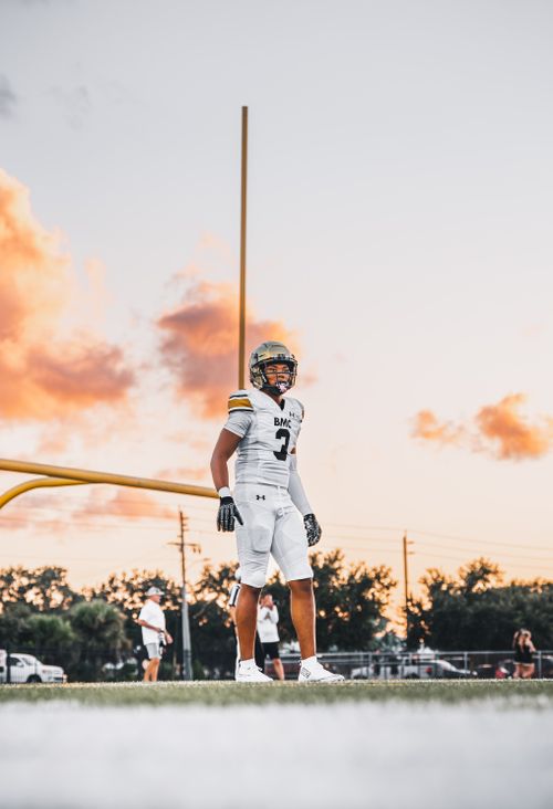 Free A young American football player stands confidently on the field at sunset, creating a dramatic athletic scene. Stock Photo