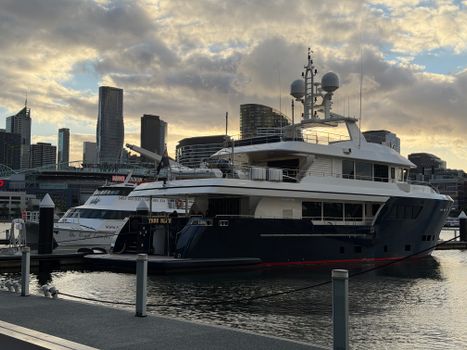 Luxury yacht docked at Southbank with Melbourne skyline at sunset.