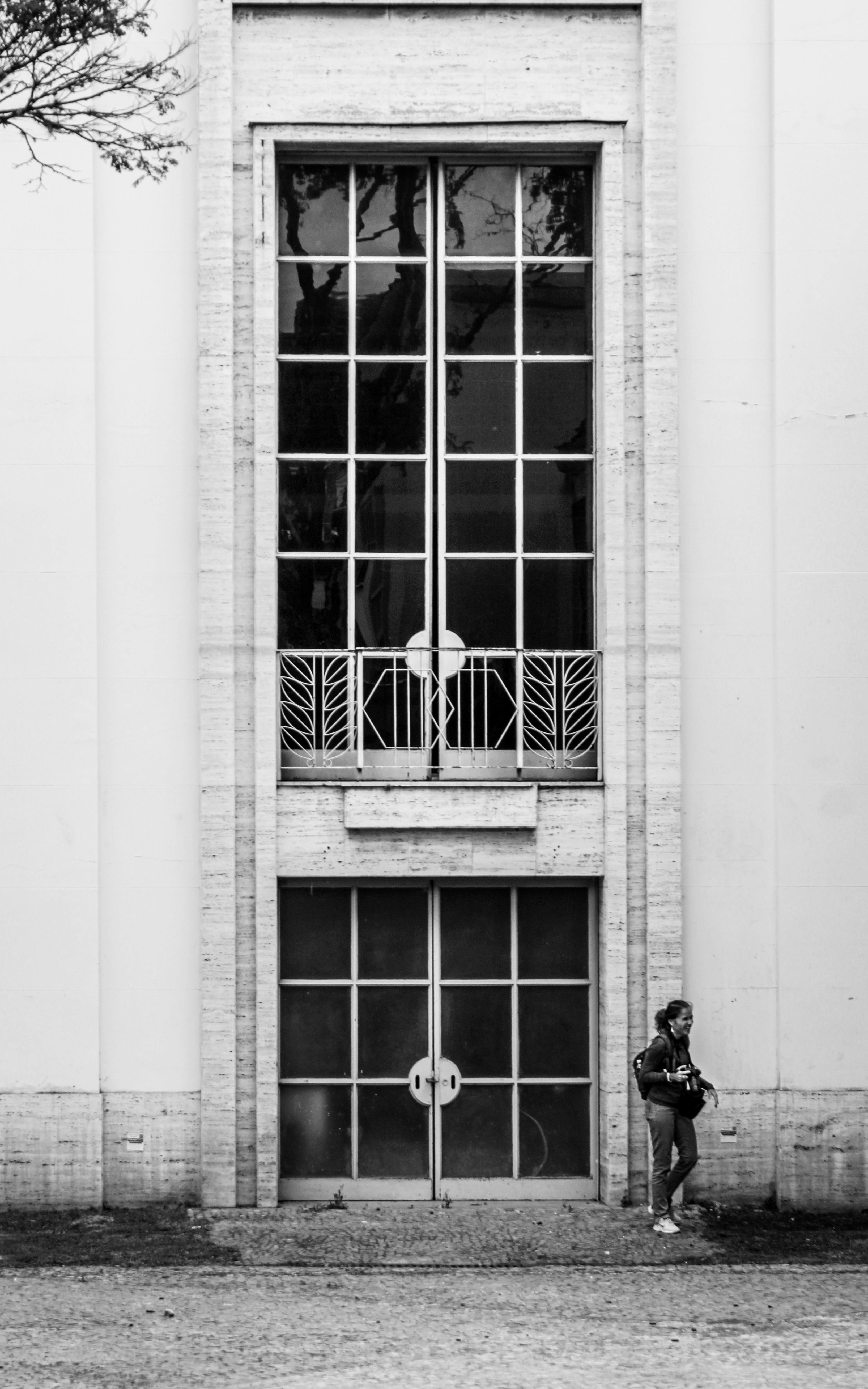 De franc Imatge en blanc i negre d'una façana d'edifici alt que captura una sola persona que passa per davant. Foto d'estoc