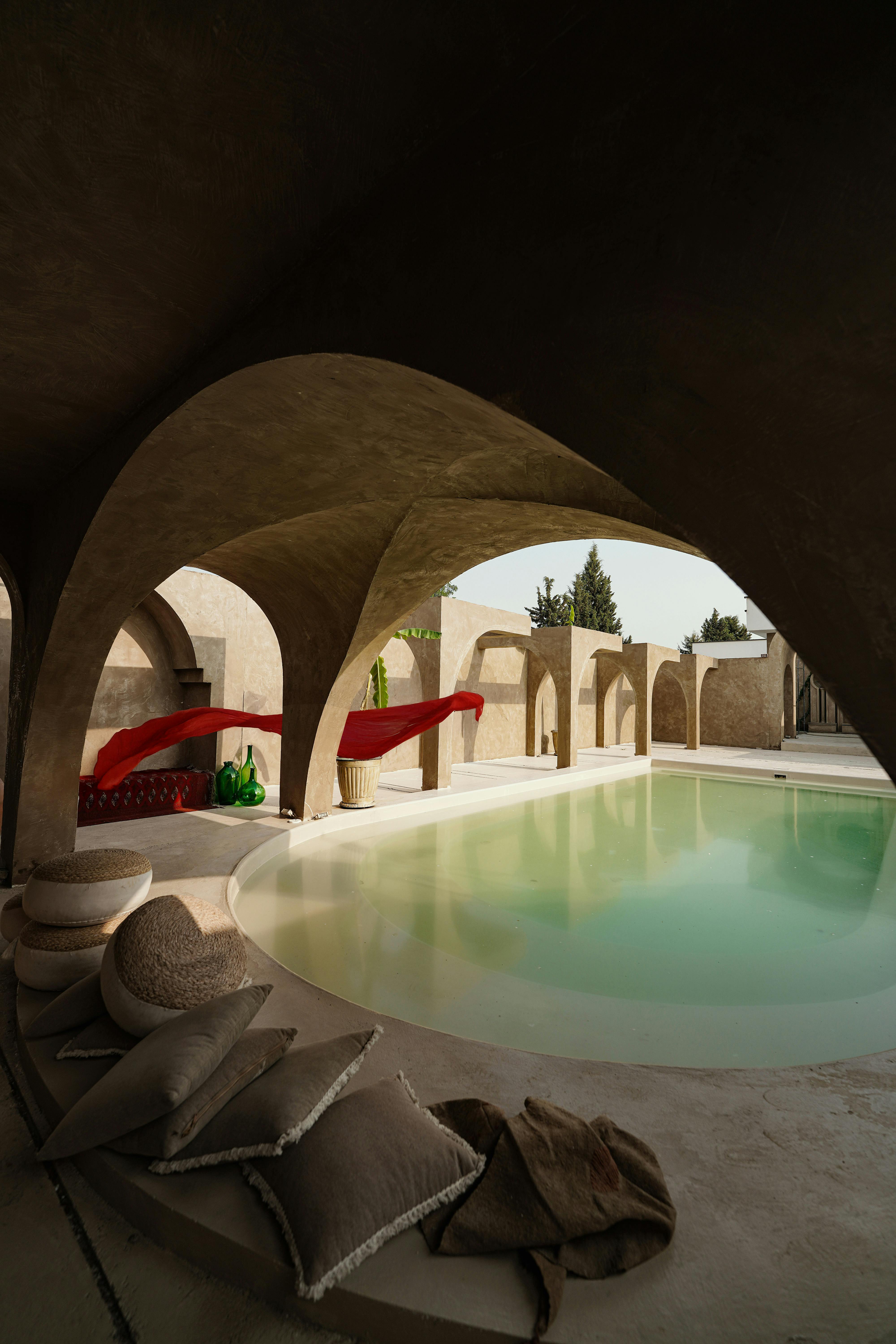Sophisticated indoor pool surrounded by elegant arches and cozy seating.
