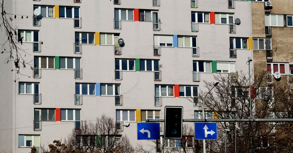 Urban apartment building with colorful window shutters and a traffic signal in the foreground.