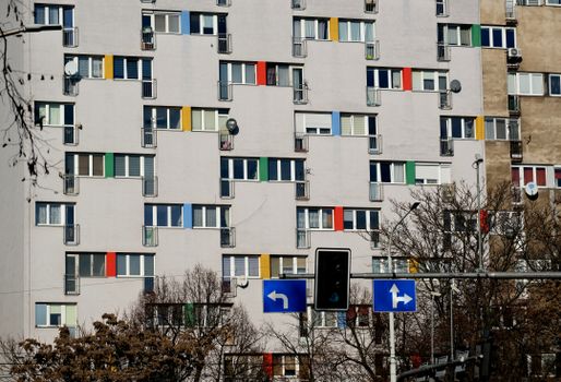 Urban apartment building with colorful window shutters and a traffic signal in the foreground.