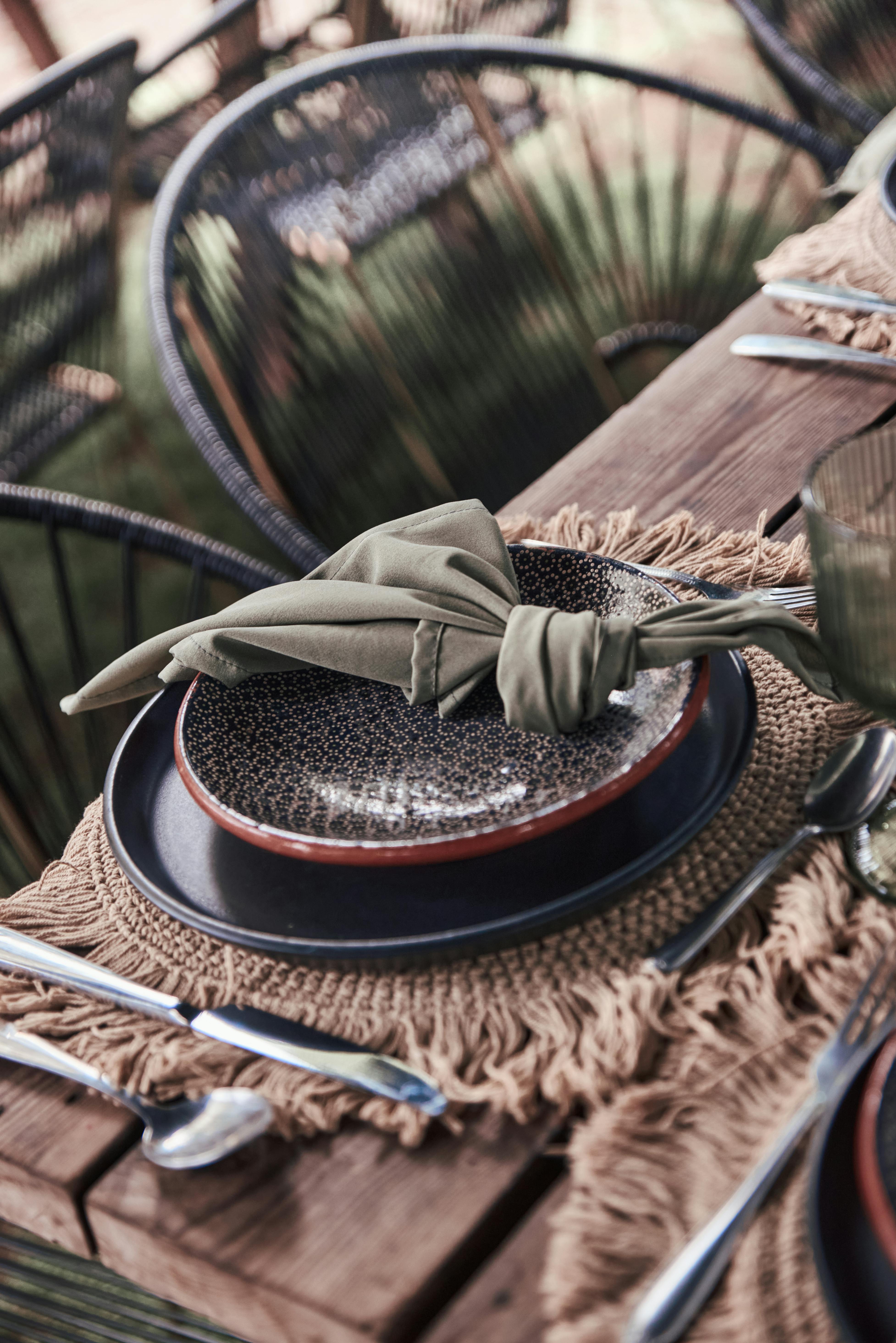 Gratis Et nærbilde av en sofistikert borddekking med en detaljert tallerken, grønn serviett og rustikk innredning. Arkivbilde