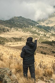 Person operating drone amidst scenic mountains with clouds.