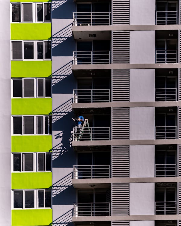 Man Standing On A Ladder On A Balcony Of A Building