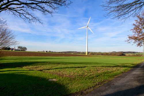 Free A wind turbine stands tall in a vast green field under a blue sky in Coesfeld, Germany. Stock Photo
