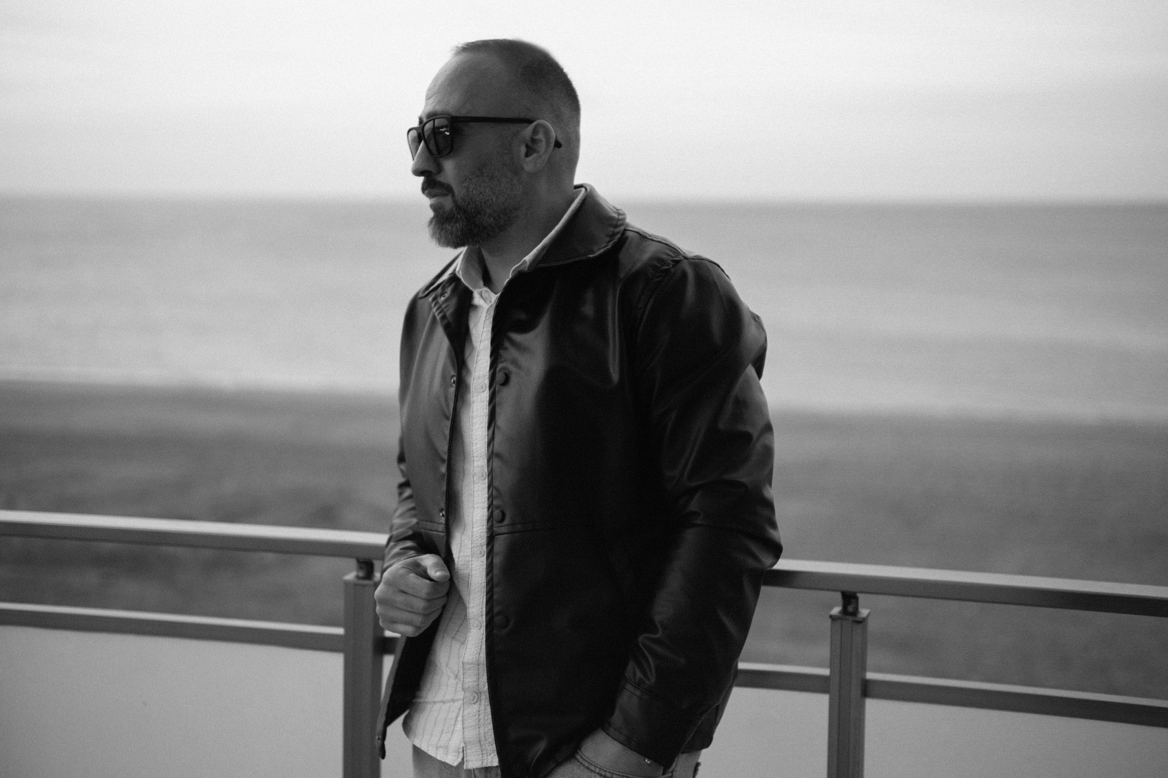 Ücretsiz Novkhani'de Hazar Denizi kıyısında deri ceket giymiş bir adamın siyah beyaz portresi. Stok Fotoğraflar