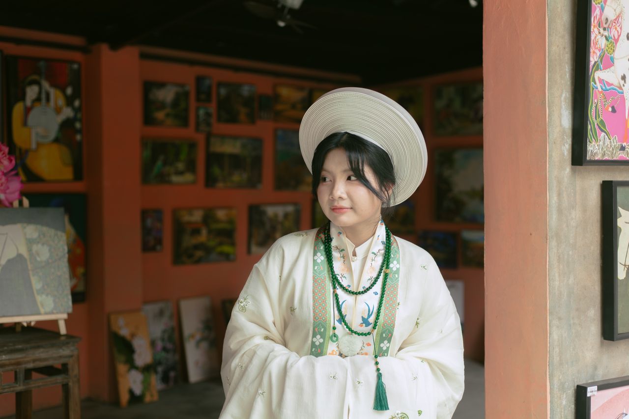 young woman in traditional asian clothing standing in an art gallery s