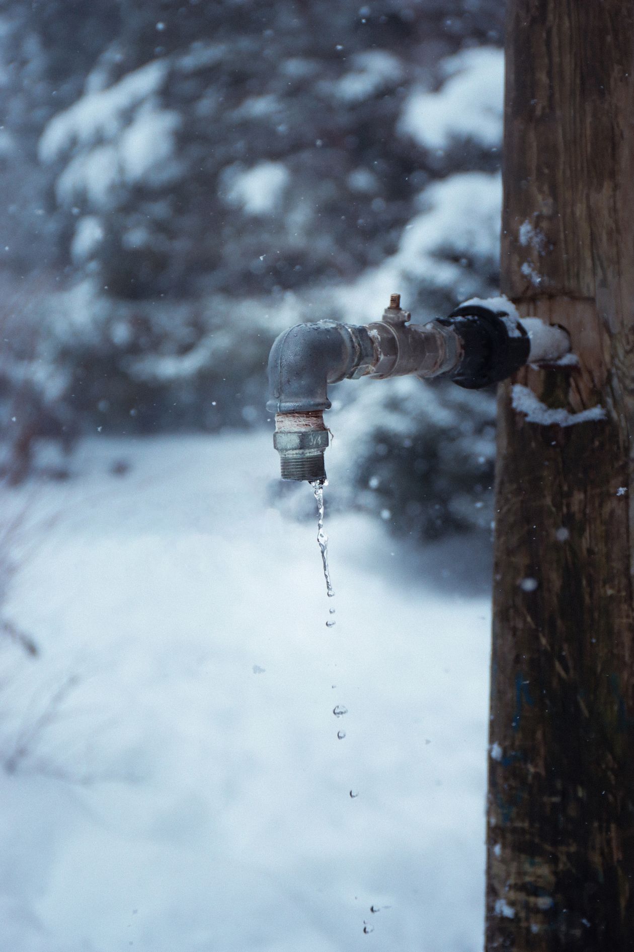 Outdoor water tap with a drip freezing in a snowy yard