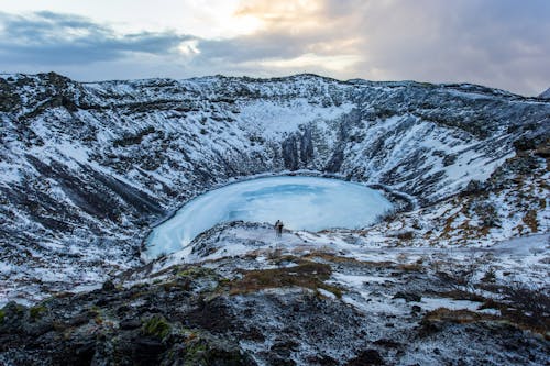 Orang Berdiri Di Formasi Batuan Dekat Gunung Yang Tertutup Salju Di Bawah Langit Berawan