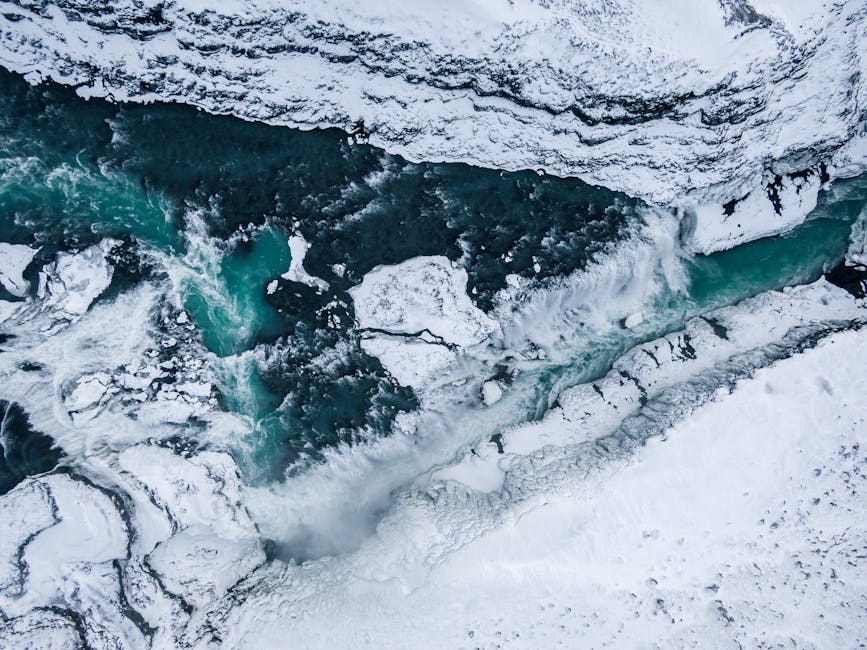 Stunning aerial shot of a frozen river in Iceland surrounded by snow, showcasing natural winter beauty.