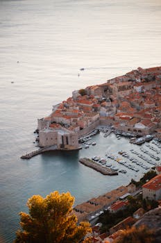 Stunning aerial view of Dubrovnik's Old Town and marina bathed in warm sunset light.