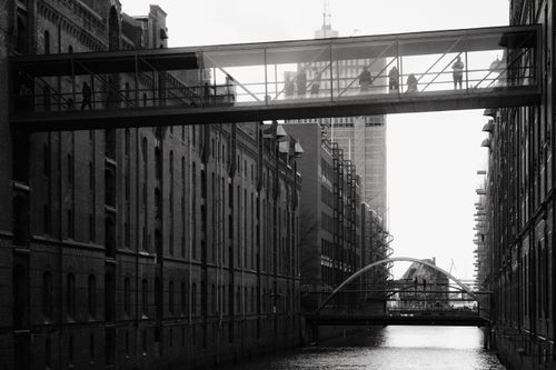 Free Black and white view of pedestrians on a bridge in Hamburg's Speicherstadt with canal below. Stock Photo